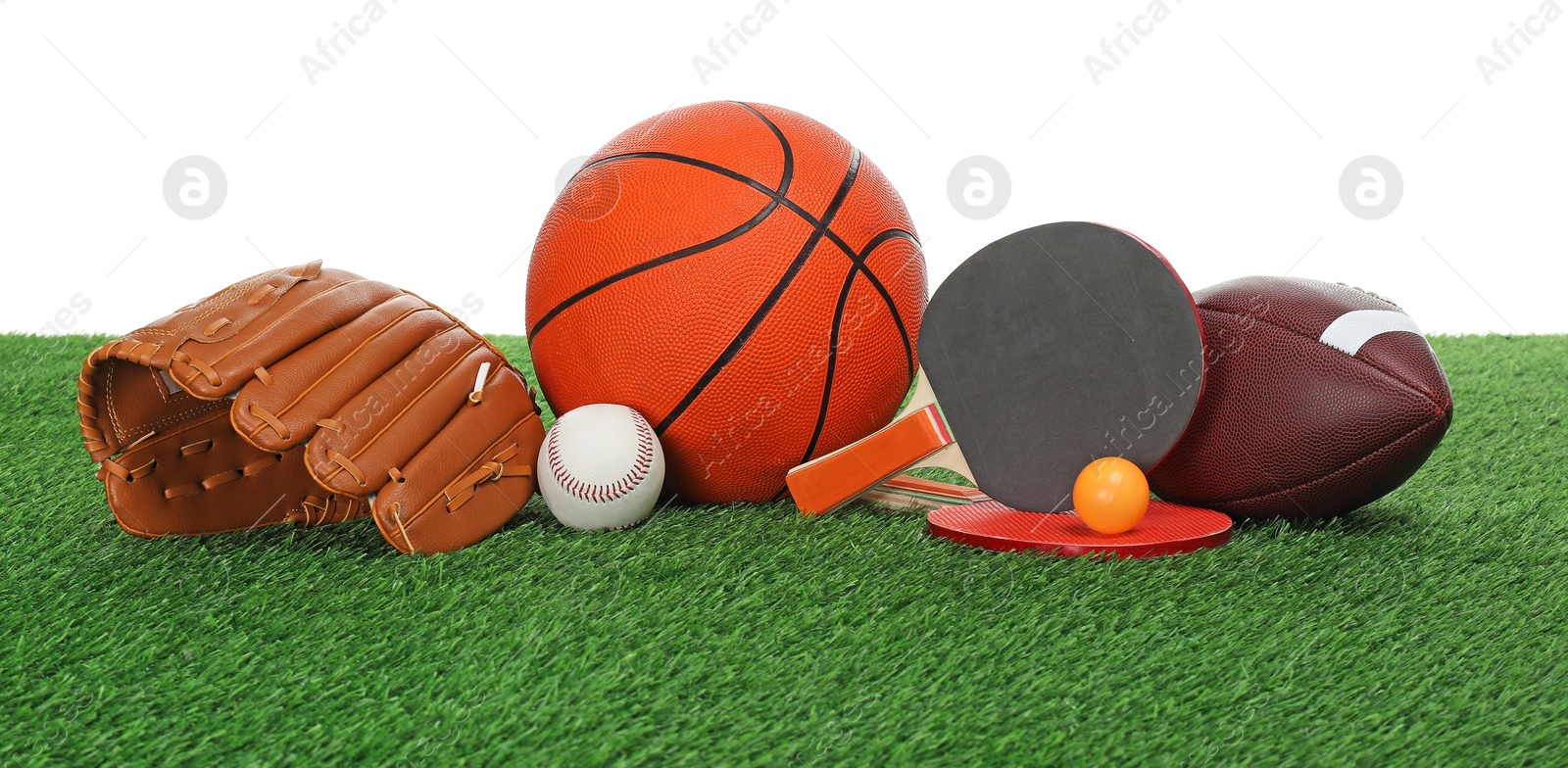 Photo of Different sport equipment on green grass against white background