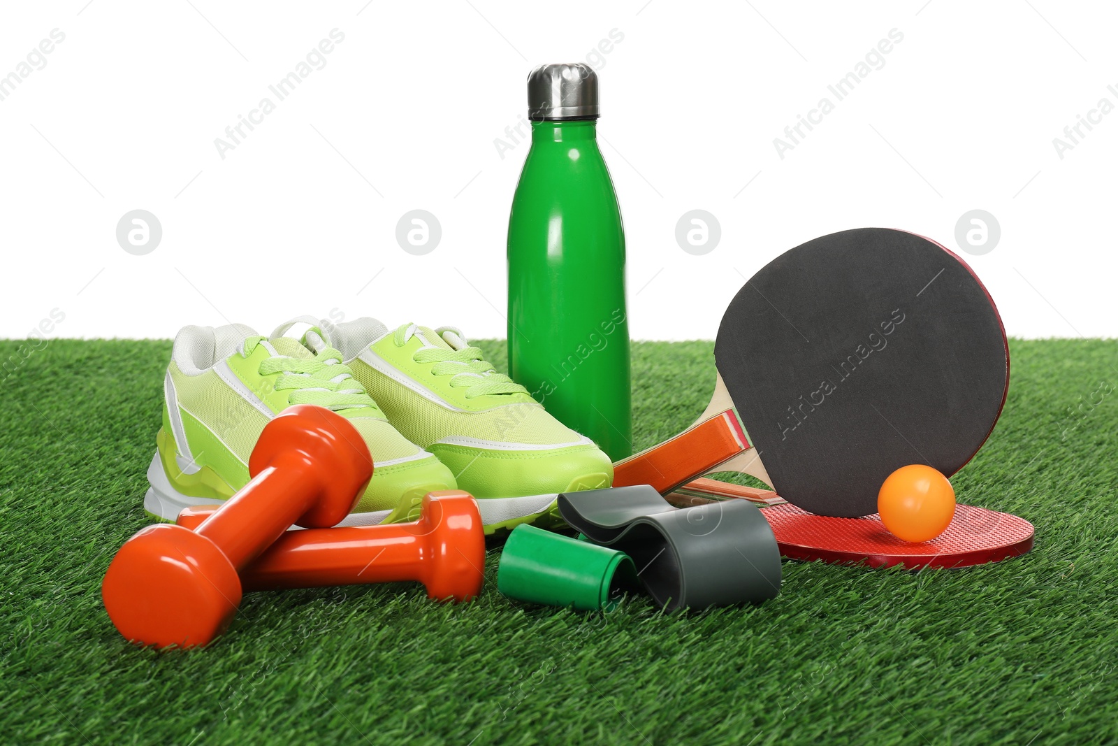 Photo of Different sport equipment on green grass against white background