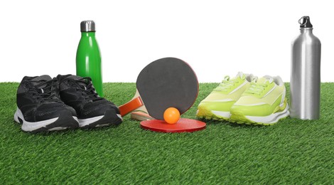 Photo of Different sport equipment on green grass against white background