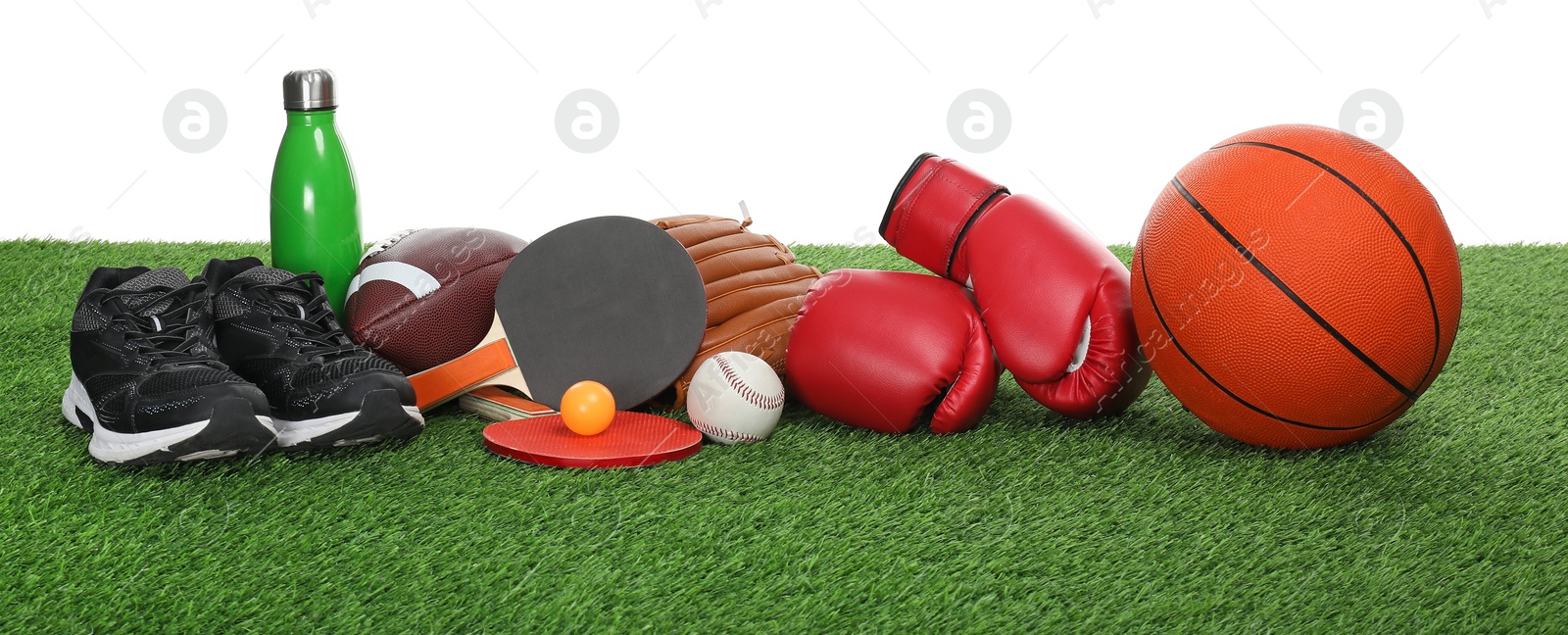 Photo of Different sport equipment on green grass against white background