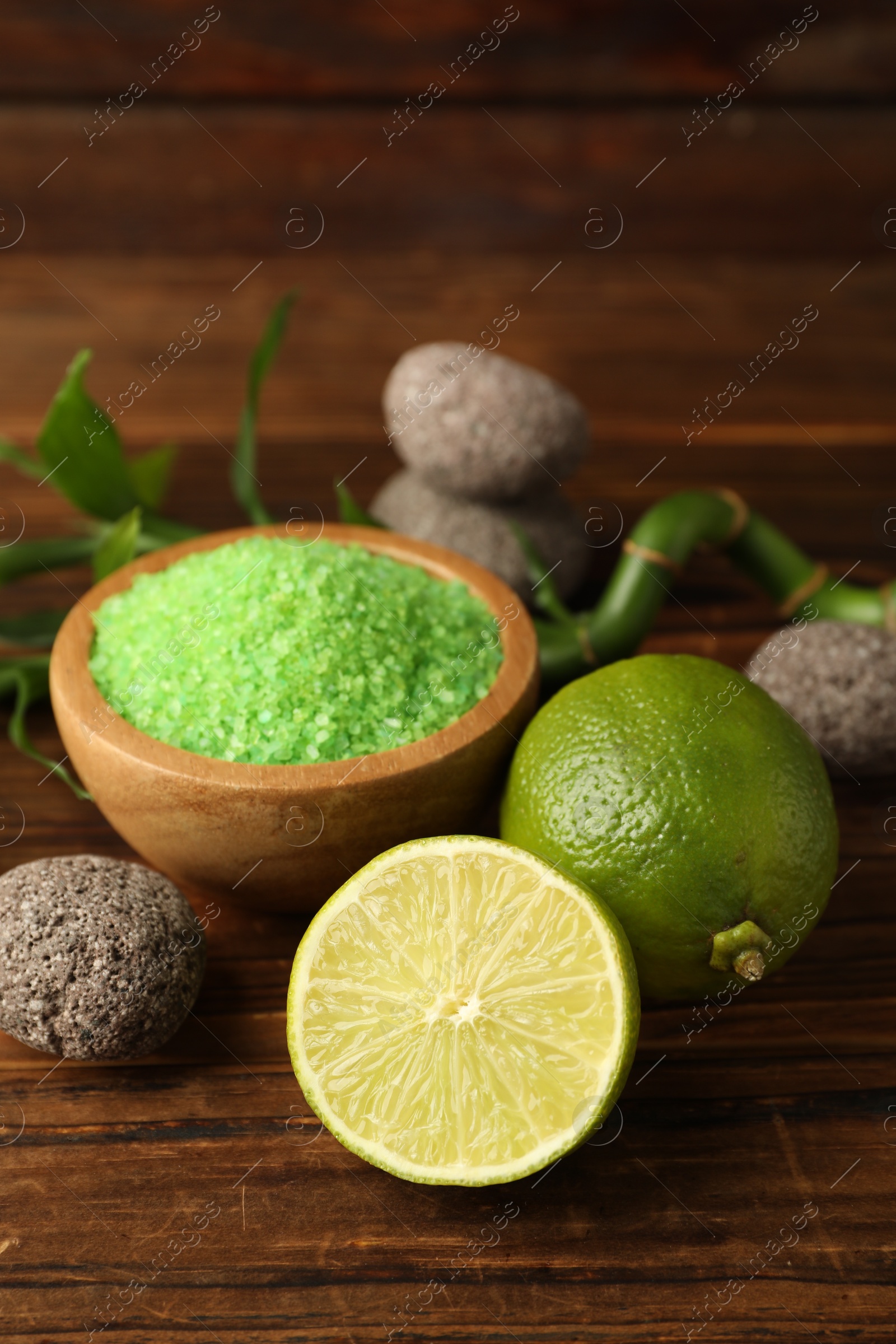 Spa composition with fresh limes, sea salt and stones on wooden table, closeup Photo of Spa composition with fresh limes, sea salt and stones on wooden table, closeup