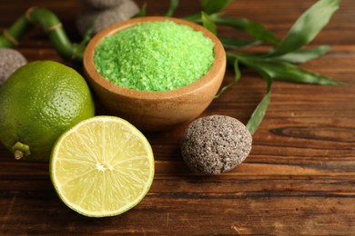 Photo of Spa composition with fresh limes, sea salt and stone on wooden table, closeup