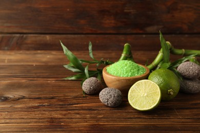 Photo of Spa composition with fresh limes, sea salt, stones and bamboo on wooden table. Space for text