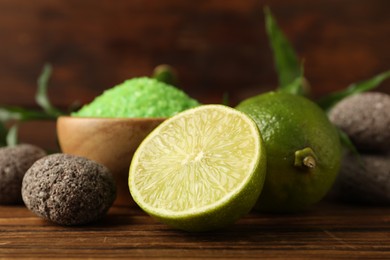 Photo of Spa composition with fresh limes, sea salt and stones on wooden table, closeup