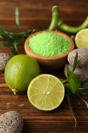 Photo of Spa composition with fresh limes, sea salt, stones and bamboo leaves on wooden table, closeup