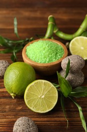 Photo of Spa composition with fresh limes, sea salt, stones and bamboo leaves on wooden table, closeup
