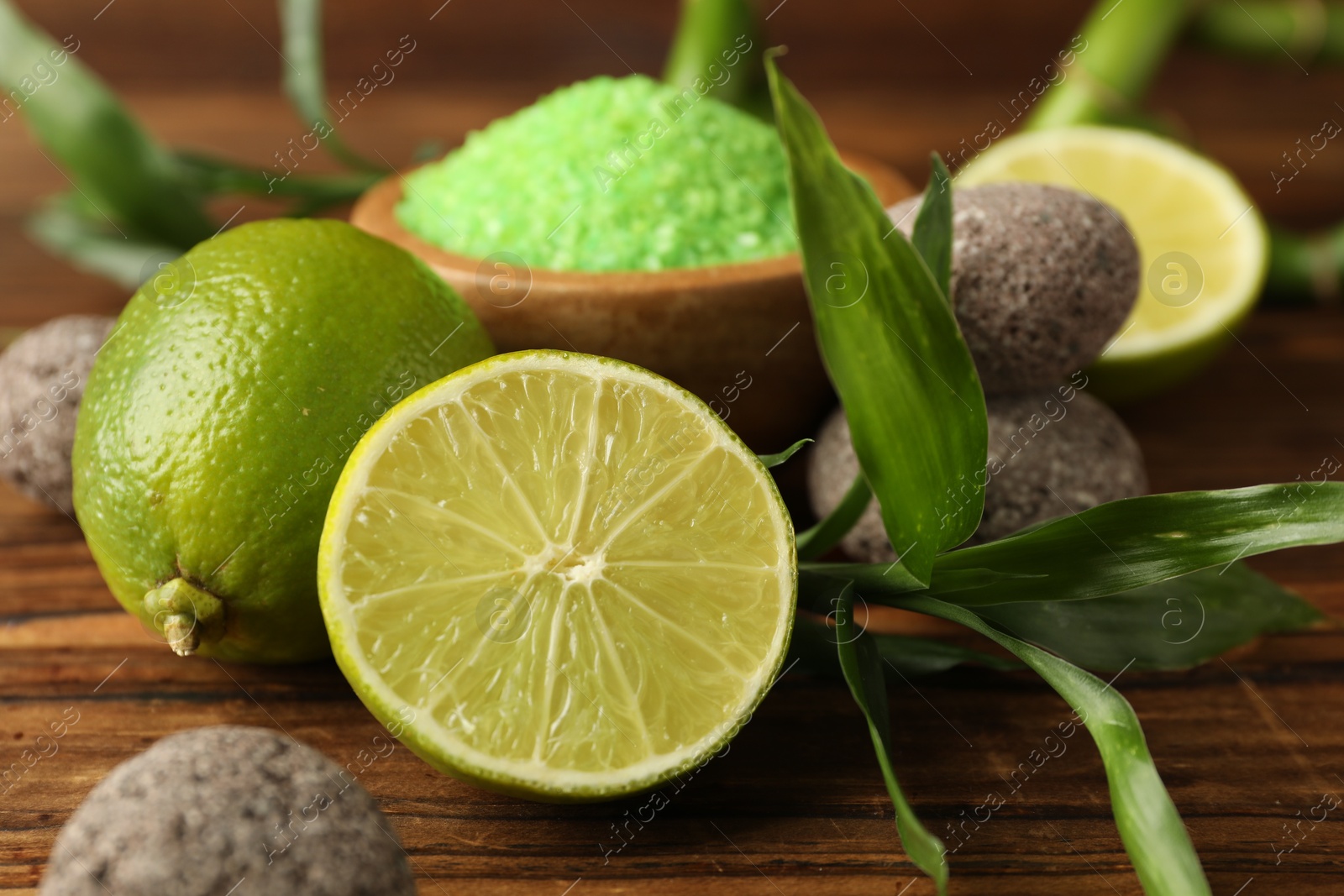 Spa composition with fresh limes, sea salt, stones and bamboo leaves on wooden table, closeup Photo of Spa composition with fresh limes, sea salt, stones and bamboo leaves on wooden table, closeup