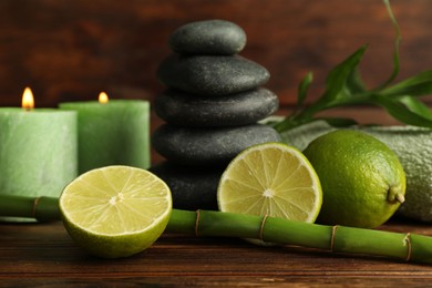 Photo of Spa composition with fresh limes, pebble stones and bamboo on wooden table, closeup