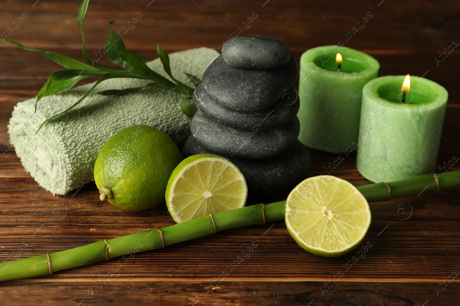 Spa composition with fresh limes, pebble stones and bamboo on wooden table, closeup Photo of Spa composition with fresh limes, pebble stones and bamboo on wooden table, closeup