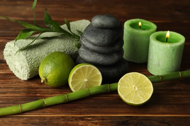Photo of Spa composition with fresh limes, pebble stones and bamboo on wooden table, closeup