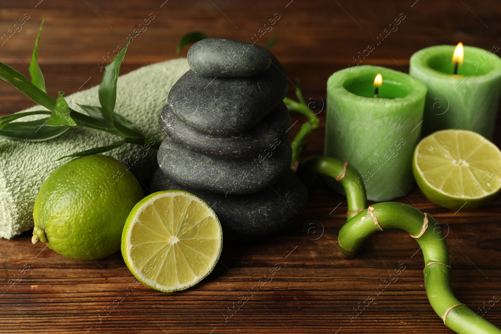 Photo of Spa composition with fresh limes, pebble stones and bamboo on wooden table, closeup