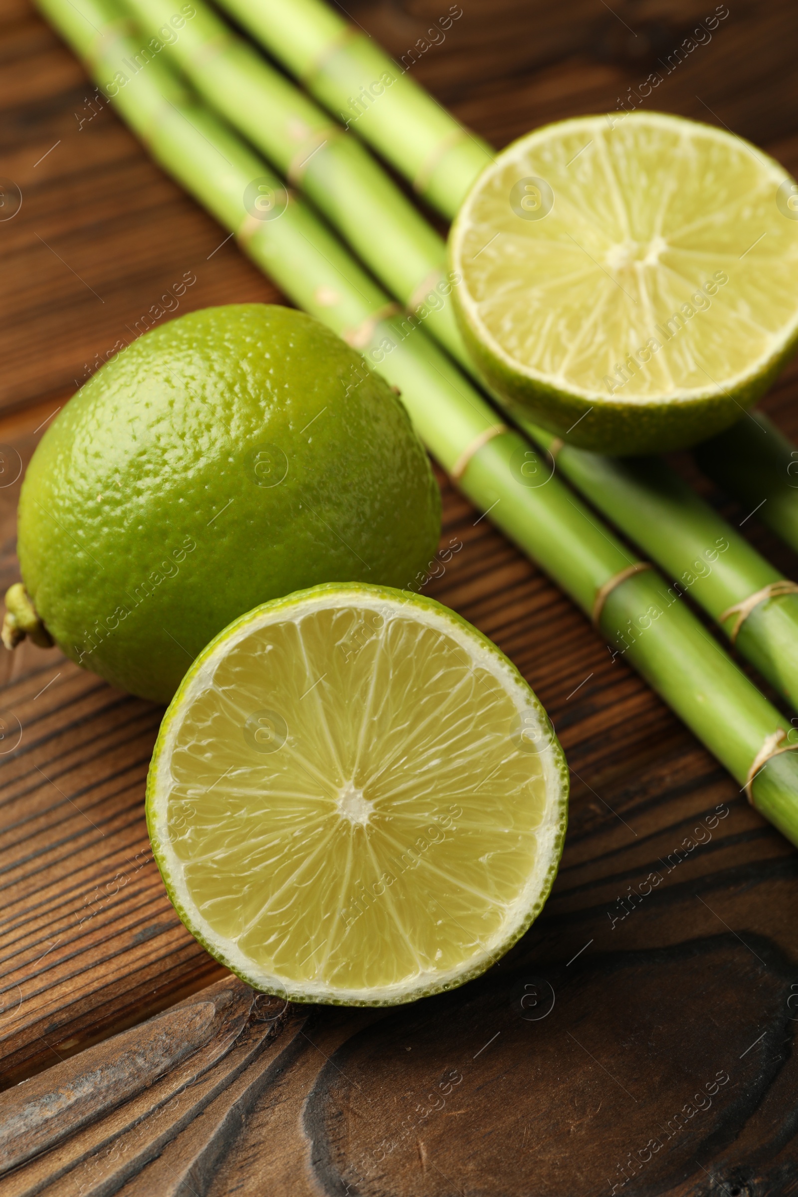Fresh limes and bamboo stems on wooden table, closeup Photo of Fresh limes and bamboo stems on wooden table, closeup