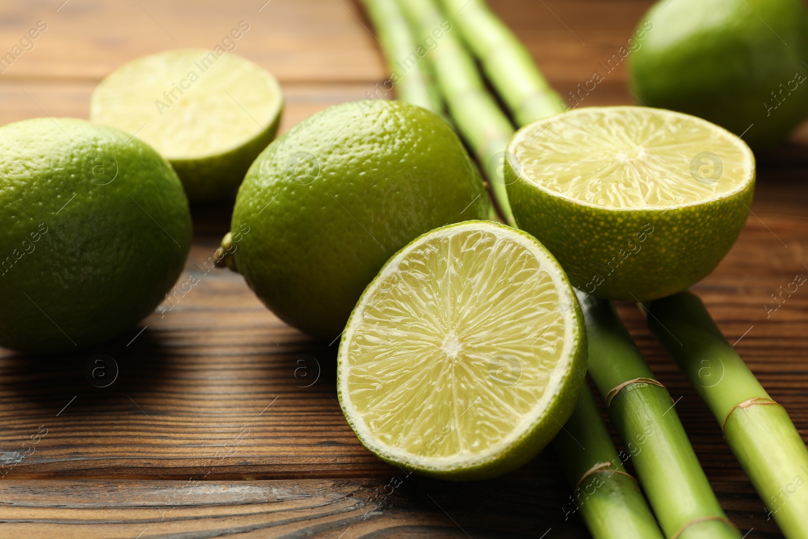 Fresh limes and bamboo stems on wooden table, closeup Photo of Fresh limes and bamboo stems on wooden table, closeup