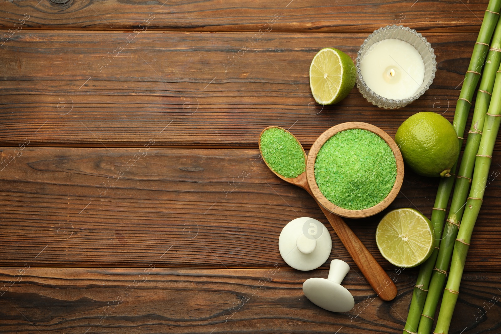 Photo of Spa composition with fresh limes, sea salt and bamboo stems on wooden table, flat lay. Space for text