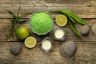 Photo of Spa composition with fresh limes, sea salt and burning candles on wooden table, flat lay