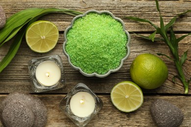 Photo of Spa composition with fresh limes, sea salt and burning candles on wooden table, flat lay
