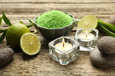 Photo of Spa composition with fresh limes, sea salt and burning candles on wooden table, closeup