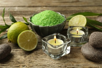 Photo of Spa composition with fresh limes, sea salt and burning candles on wooden table, closeup