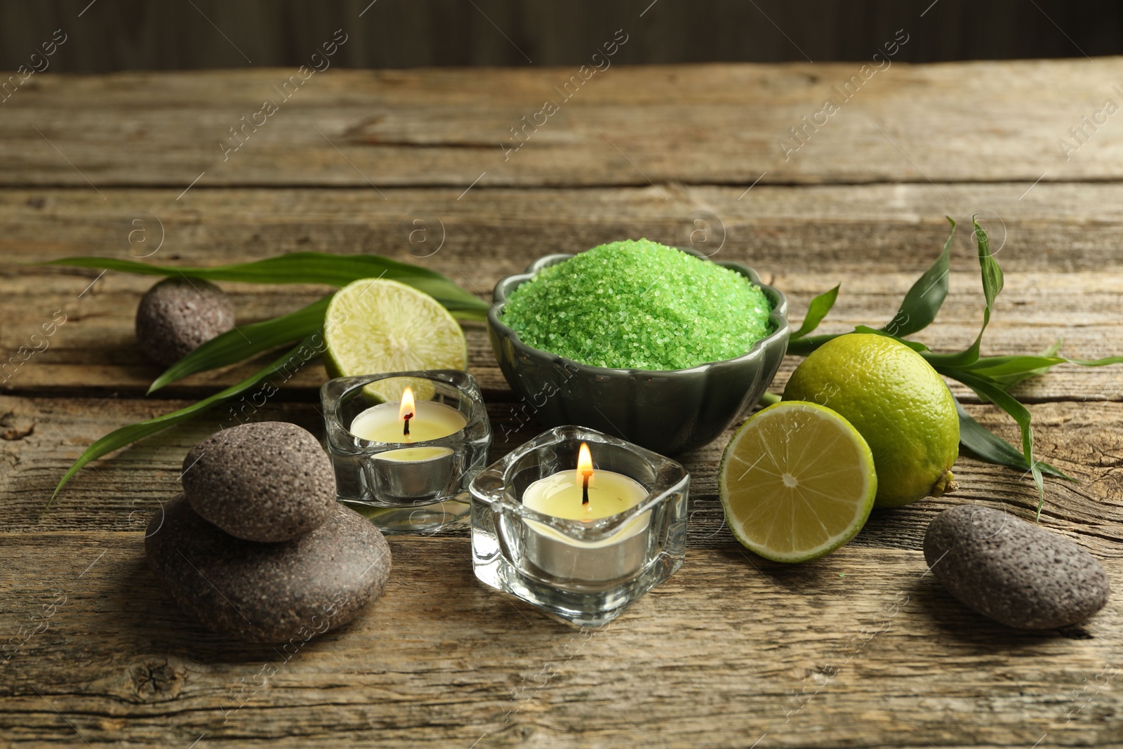Spa composition with fresh limes, sea salt and burning candles on wooden table Photo of Spa composition with fresh limes, sea salt and burning candles on wooden table