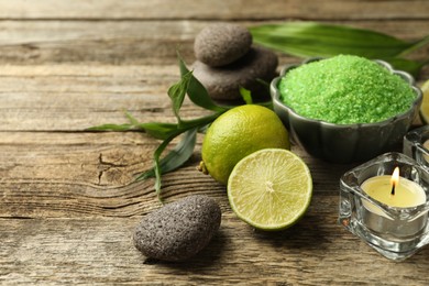 Photo of Spa composition with fresh limes, sea salt and burning candle on wooden table, closeup. Space for text