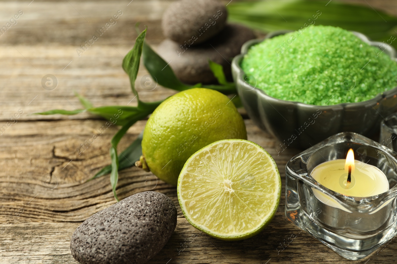 Spa composition with fresh limes, sea salt and burning candles on wooden table, closeup Photo of Spa composition with fresh limes, sea salt and burning candles on wooden table, closeup