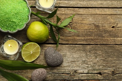 Photo of Spa composition with fresh limes, sea salt and burning candles on wooden table, flat lay. Space for text
