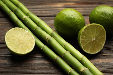 Photo of Fresh limes and bamboo stems on wooden table, closeup