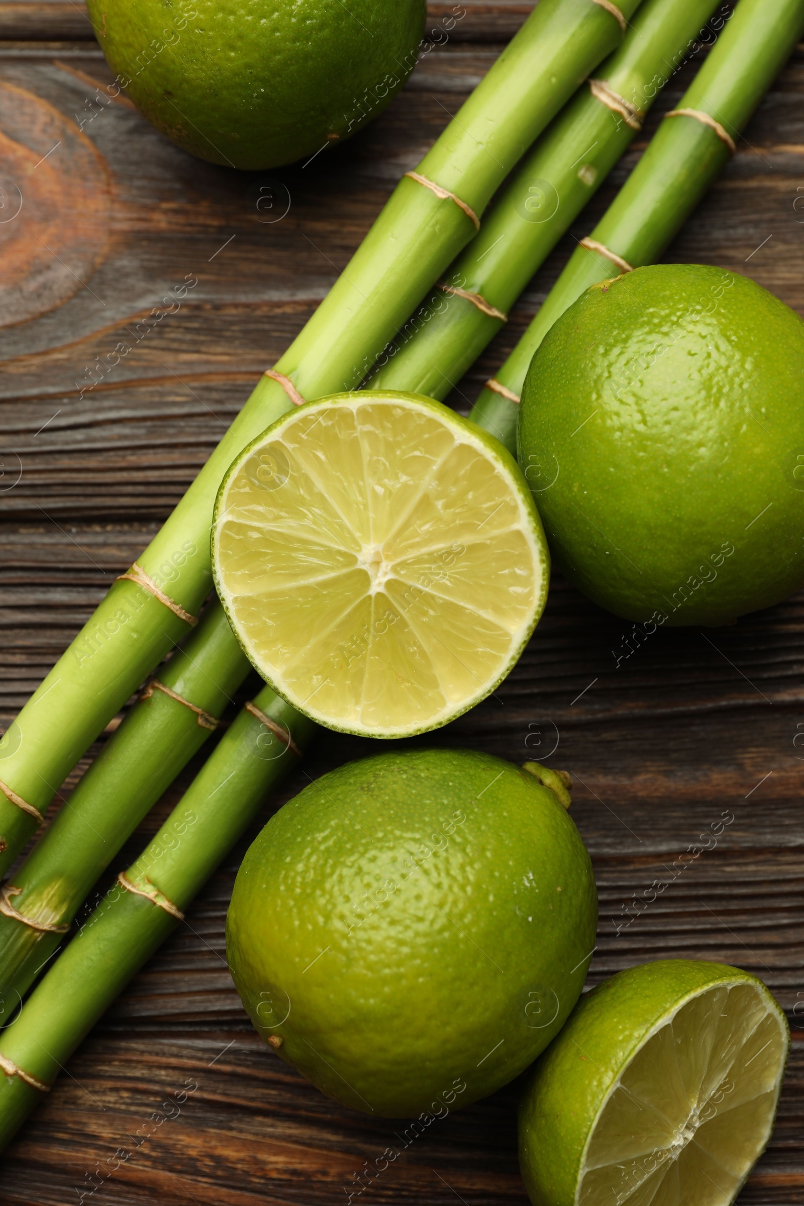 Fresh limes and bamboo stems on wooden table, flat lay Photo of Fresh limes and bamboo stems on wooden table, flat lay