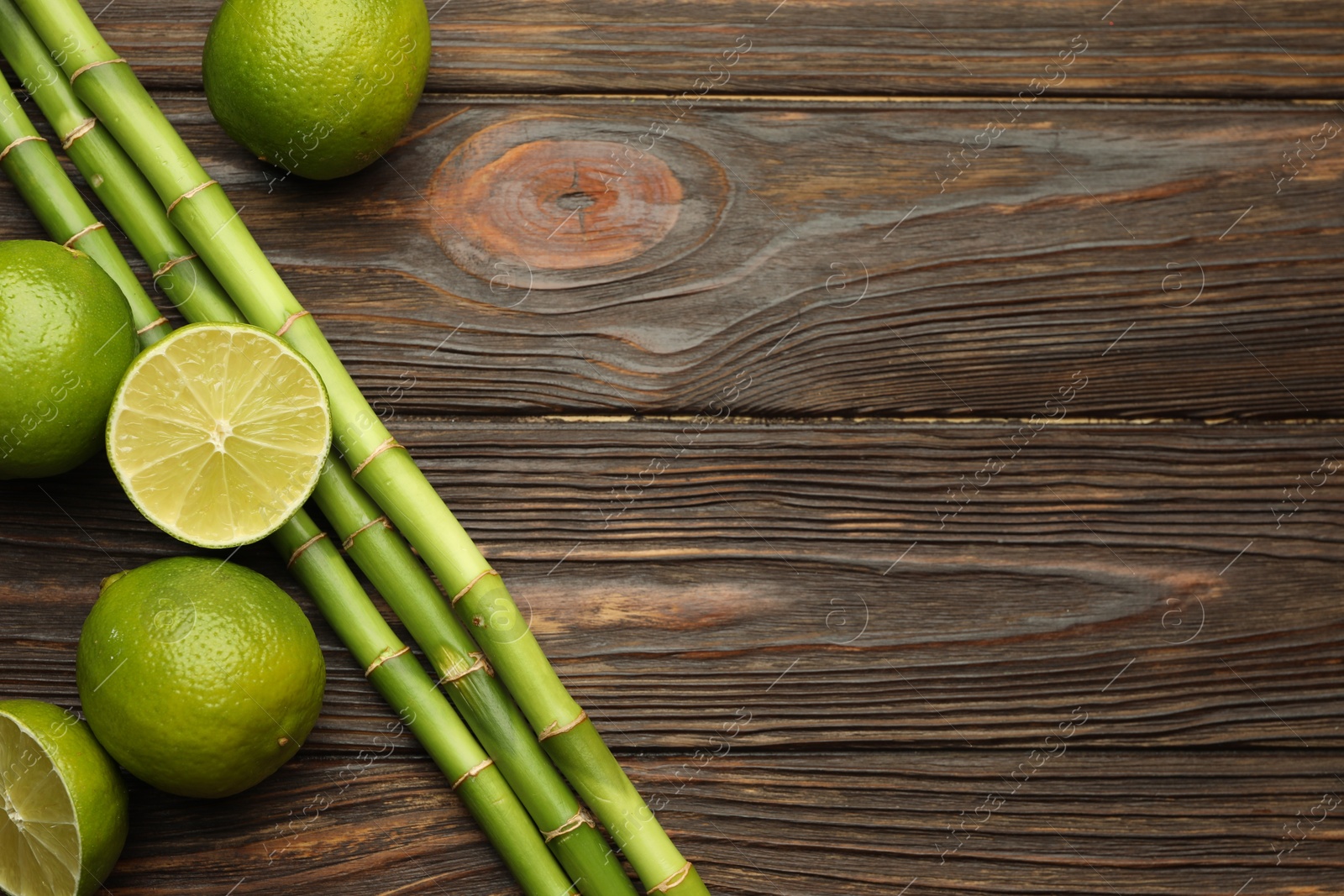 Fresh limes and bamboo stems on wooden table, flat lay. Space for text Photo of Fresh limes and bamboo stems on wooden table, flat lay. Space for text