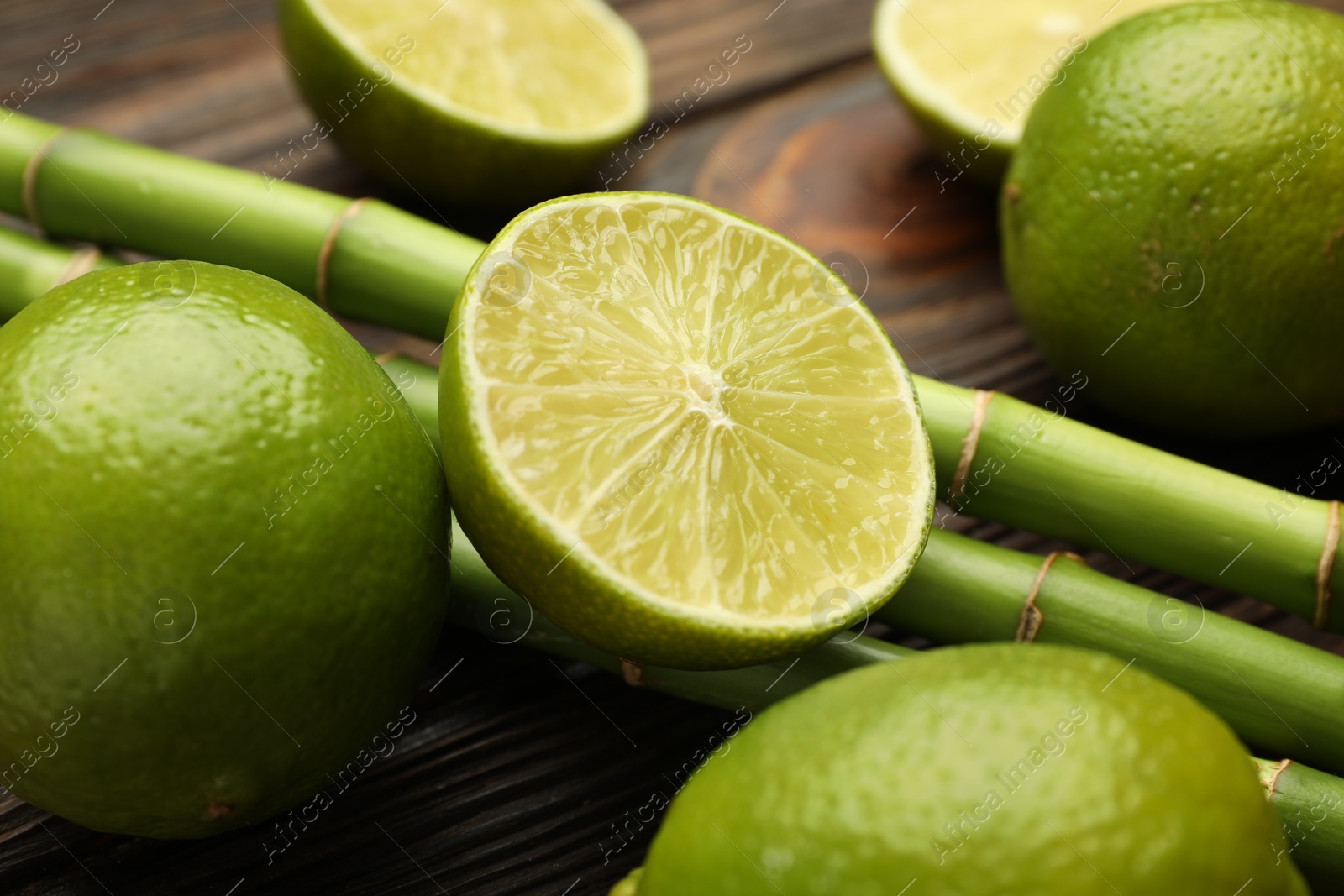 Fresh limes and bamboo stems on wooden table, closeup Photo of Fresh limes and bamboo stems on wooden table, closeup