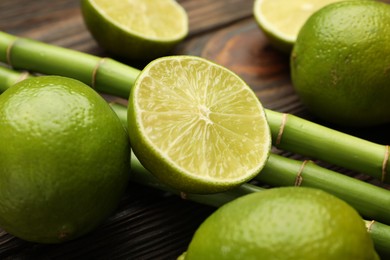 Photo of Fresh limes and bamboo stems on wooden table, closeup