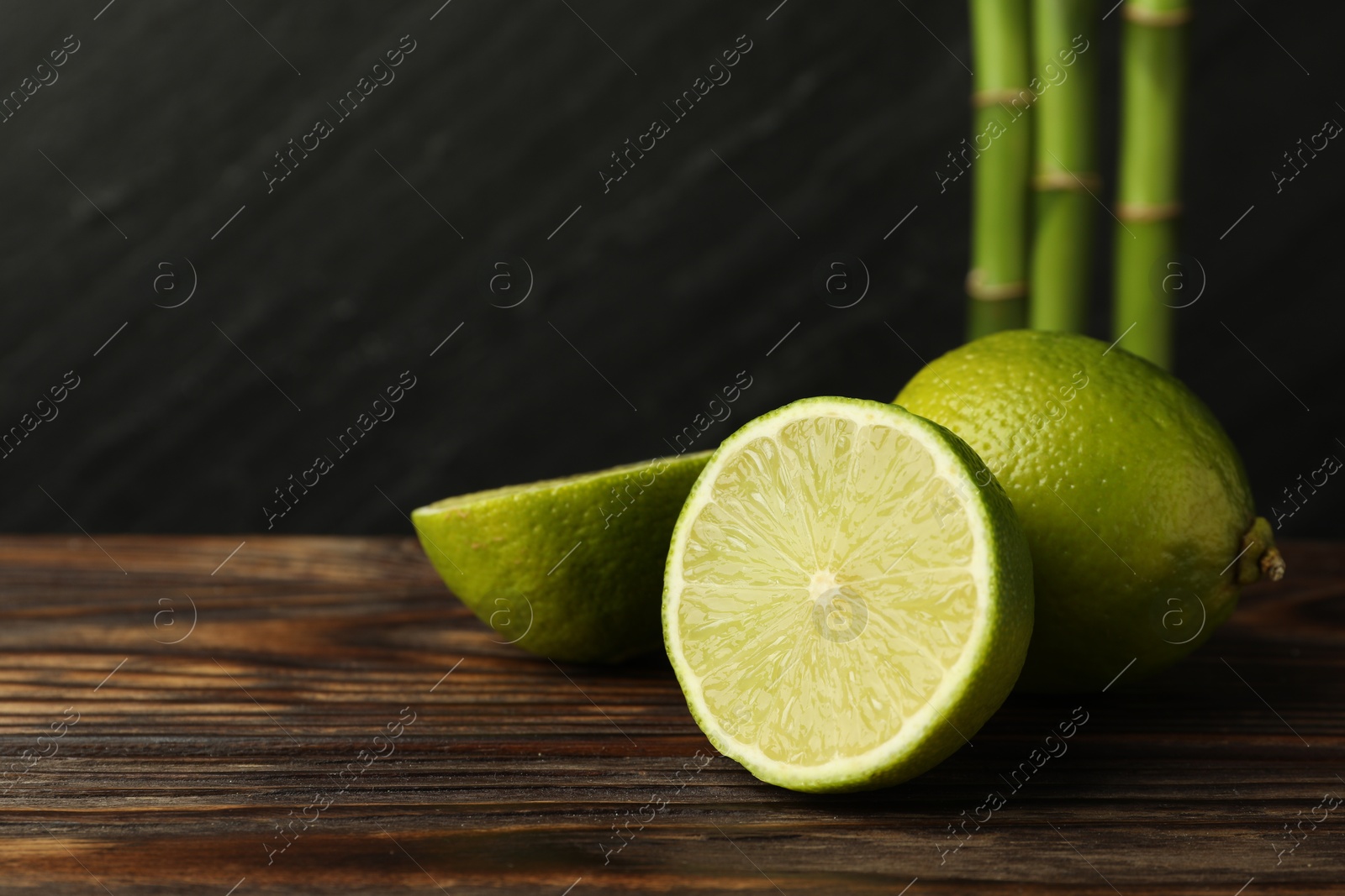 Fresh limes on wooden table against dark background, closeup. Space for text Photo of Fresh limes on wooden table against dark background, closeup. Space for text
