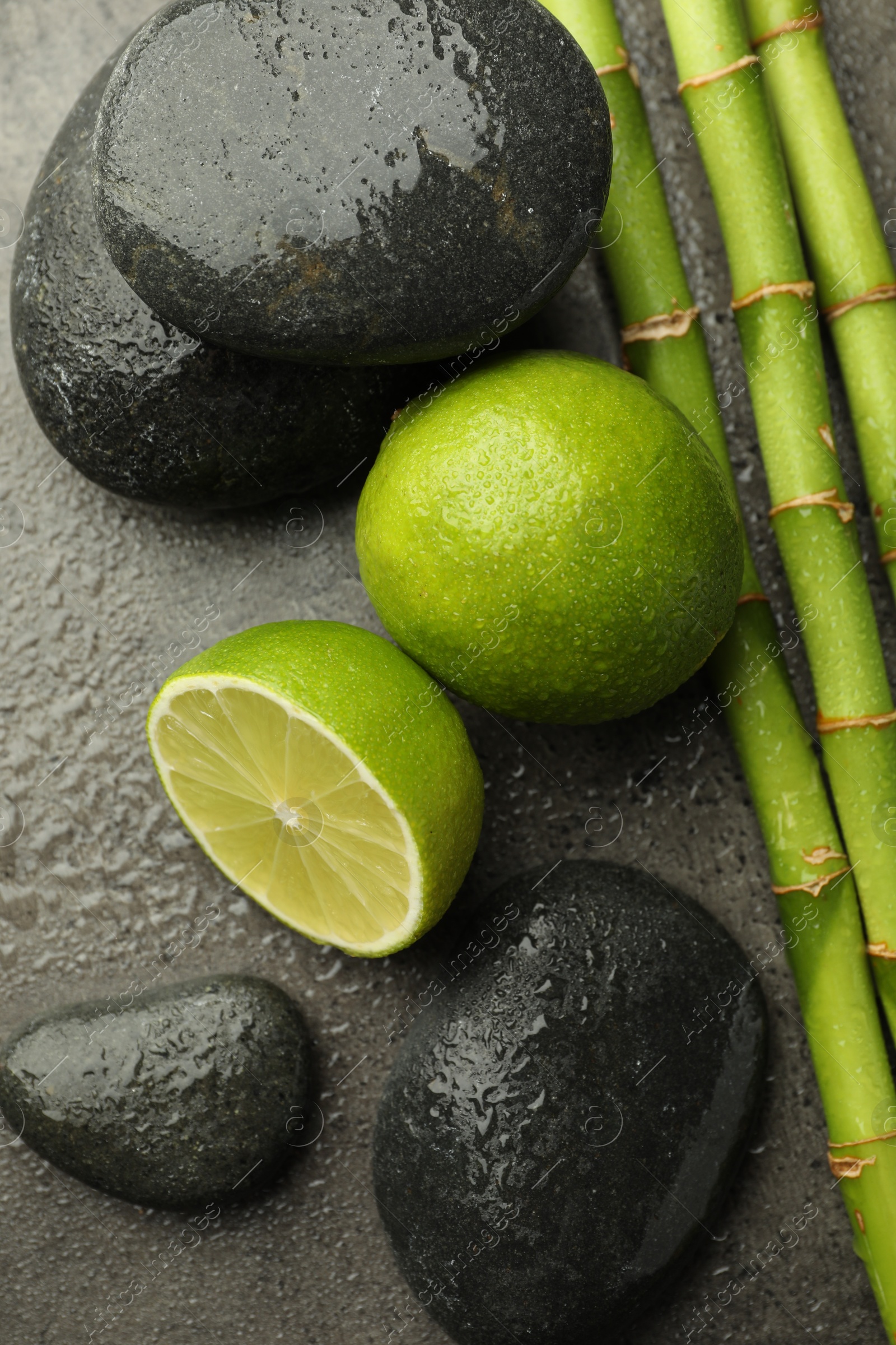 Spa composition with wet limes, pebble stones and bamboo stems on grey table, flat lay Photo of Spa composition with wet limes, pebble stones and bamboo stems on grey table, flat lay
