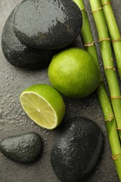 Photo of Spa composition with wet limes, pebble stones and bamboo stems on grey table, flat lay