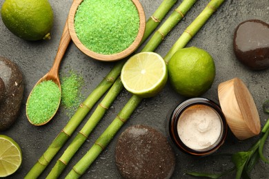 Photo of Spa composition with wet limes, sea salt, pebble stones and bamboo stems on grey table, flat lay