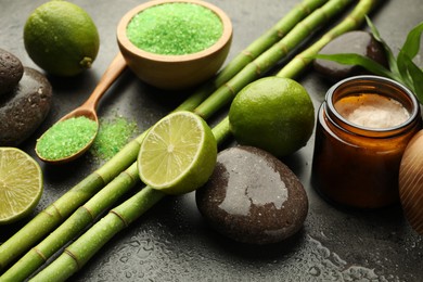 Photo of Spa composition with wet limes, sea salt, pebble stones and bamboo stems on grey table, closeup