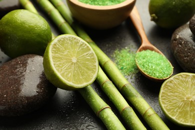 Photo of Spa composition with wet limes, sea salt, pebble stones and bamboo stems on grey table, closeup