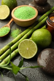 Photo of Spa composition with wet limes, sea salt, pebble stones and bamboo on grey table