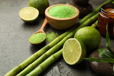Photo of Spa composition with wet limes, sea salt, pebble stone and bamboo on grey table, closeup