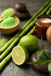 Photo of Spa composition with wet limes, sea salt, pebble stones and bamboo on grey table