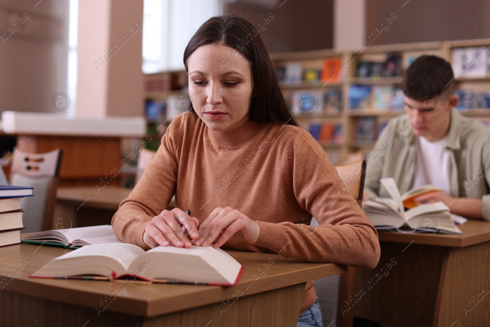 Photo of Beautiful woman with books at desk in public library