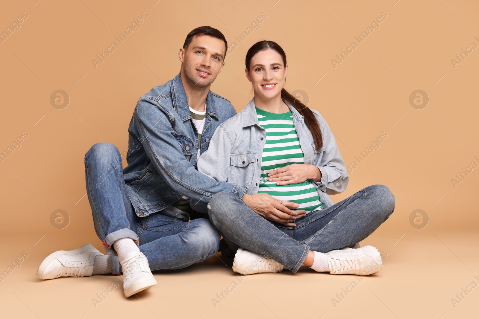 Photo of Pregnant woman and her husband on beige background