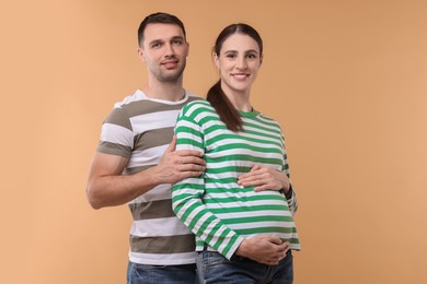 Photo of Pregnant woman and her husband on beige background