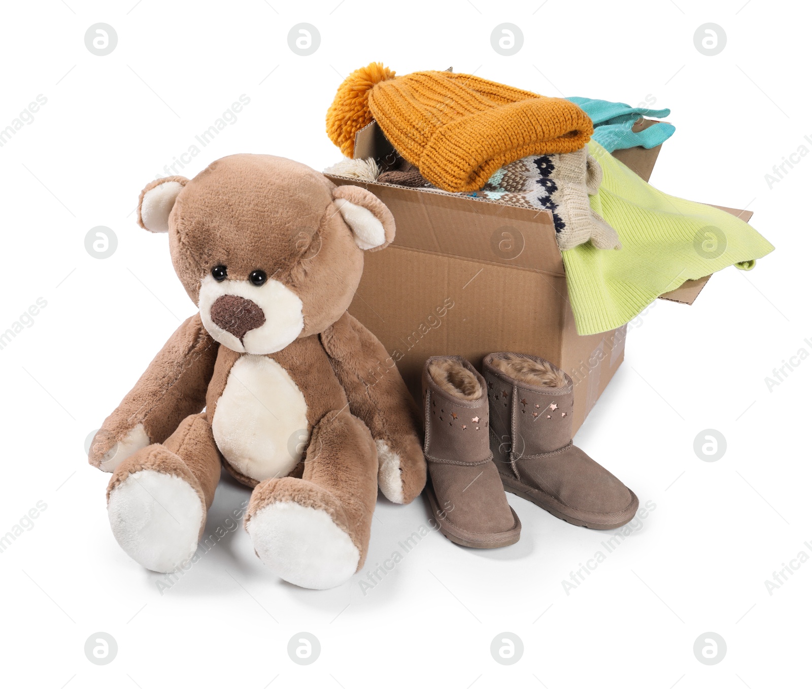 Photo of Different used clothes in box, teddy bear and boots isolated on white