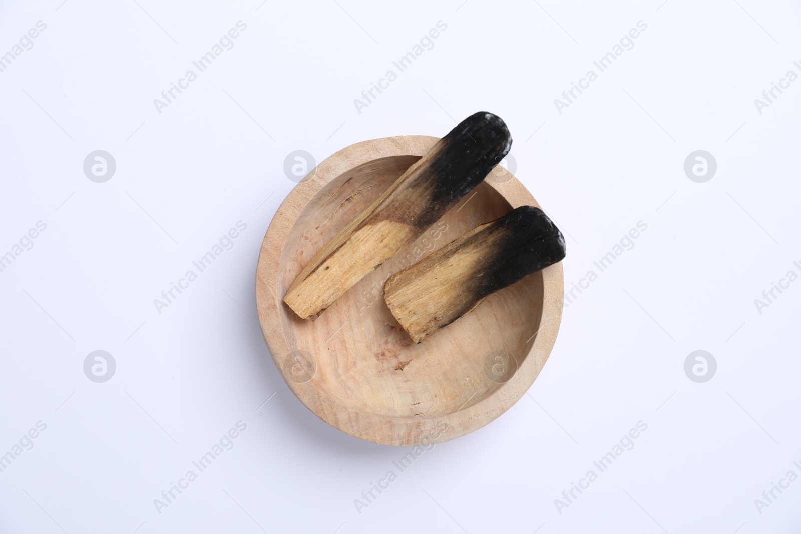 Photo of Burnt palo santo sticks in wooden bowl on white background, top view