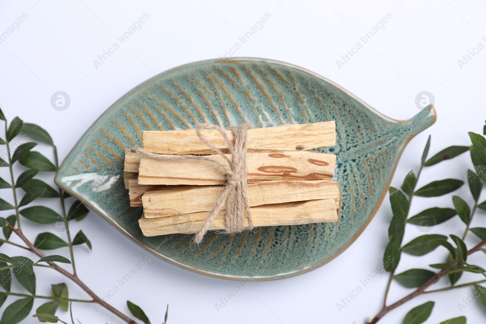 Photo of Bunch of palo santo sticks and green branches on white background, flat lay