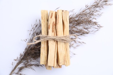 Photo of Bunch of palo santo sticks and dried reed on white background, top view