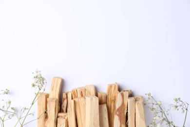 Photo of Palo santo sticks and gypsophila flowers on white background, flat lay. Space for text