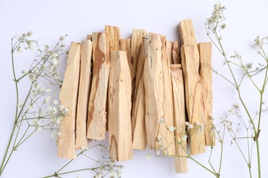 Photo of Palo santo sticks and gypsophila flowers on white background, flat lay