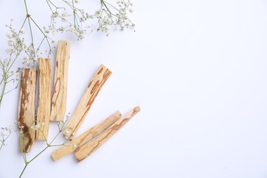 Photo of Palo santo sticks and gypsophila flowers on white background, flat lay. Space for text